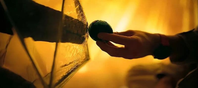 A hand offering a small object through an illuminated opening